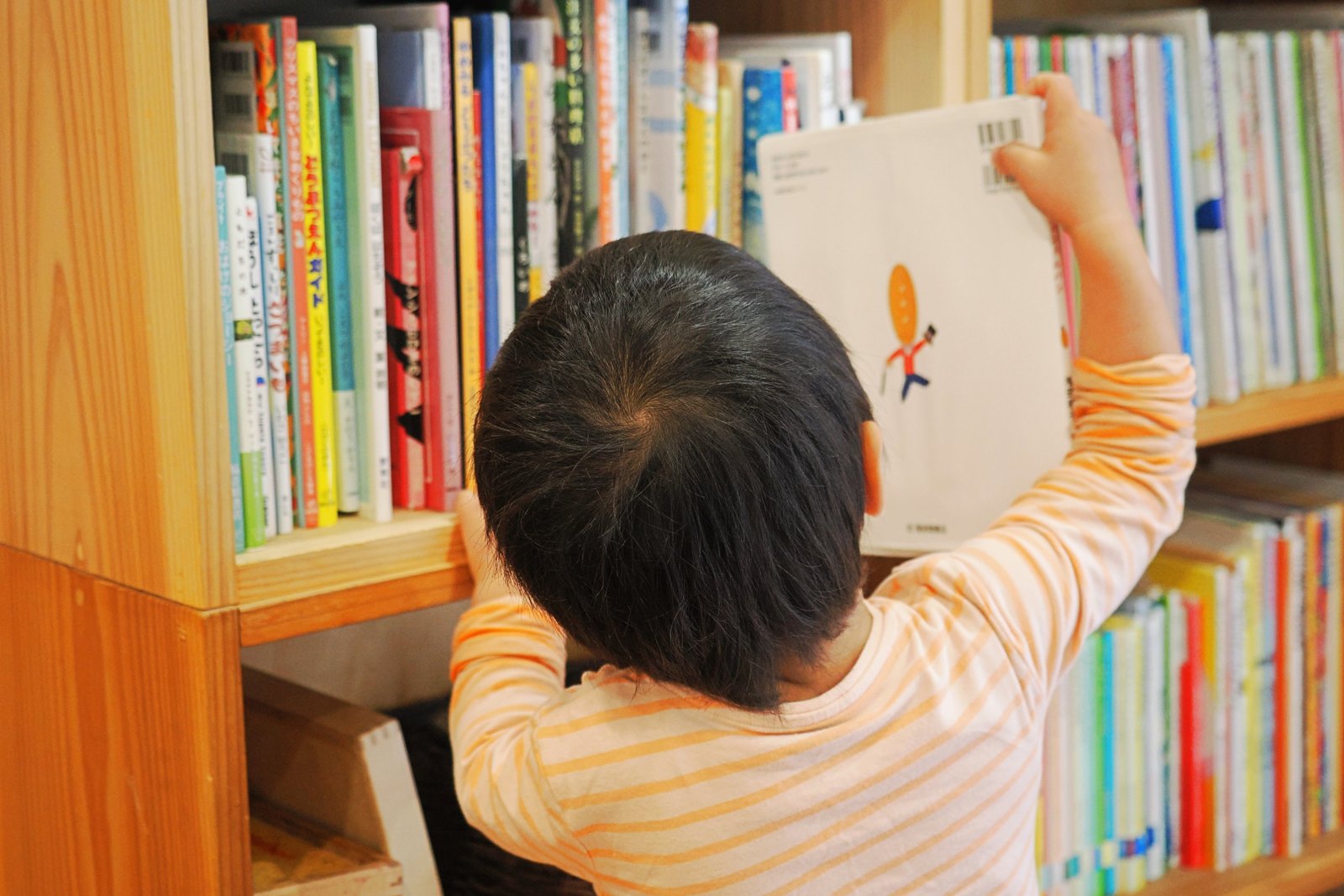 絵本棚から絵本を選ぶ子ども